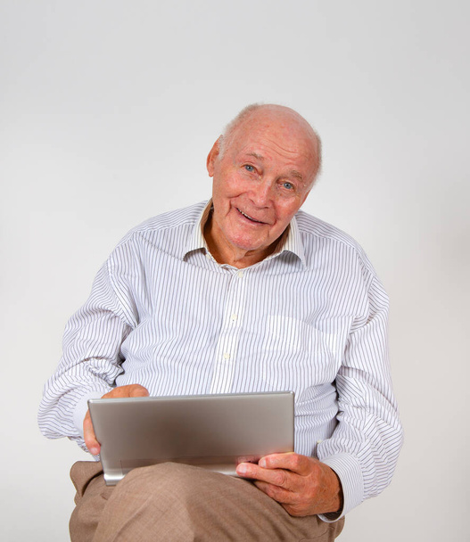 šťastný starší muž sedí na židli a pracuje se svým notebookem - Fotografie, Obrázek