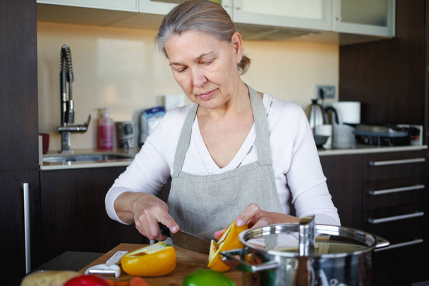 Зріла жінка на кухні готує їжу
 - Фото, зображення