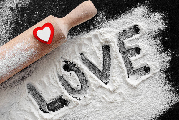 Preparation for baking home made cookie or pizza for Valentine's Day. Top view, flat lay. rolling pin, flour, red and white heart and text love. St Valentines Day ornament food background. - Photo, Image