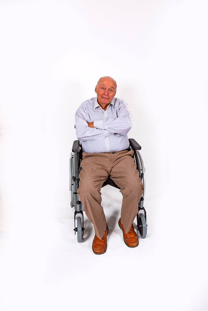 Χαρούμενος ηλικιωμένος κάθεται χαμογελώντας στην αναπηρική του καρέκλα - Φωτογραφία, εικόνα