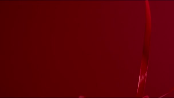 セクシーなムードダークレッドのシルクリボンが赤い背景に落ちています。FHDはまだ高品質のビデオを撮影. - 映像、動画