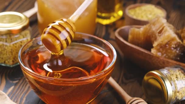 Miel en frasco de vidrio con cazo de miel sobre fondo de madera - Imágenes, Vídeo