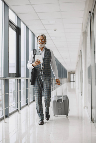 Senior businessman with travel suitcase in airport - Фото, изображение