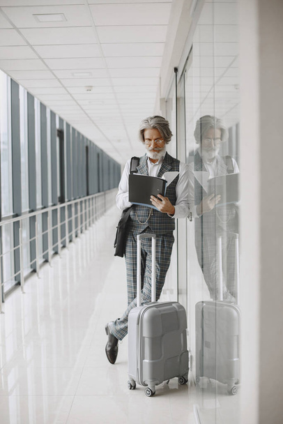 Senior businessman with travel suitcase in airport - Foto, afbeelding