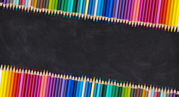 Rand van kleurrijke houten potloden in leunende rij op een leeg schoolbord, terug naar school concept. - Foto, afbeelding