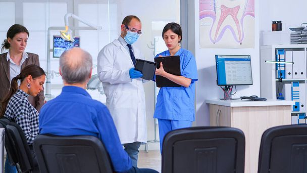 Especialista em Odontologia falando com assistente em pé na sala de espera - Foto, Imagem