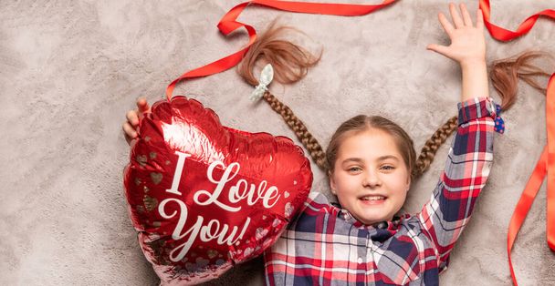 cute smiling girl holding red heart shaped balloon. Caucasian beautiful happy model having fun, birthday or Valentines day concepts. - Photo, Image