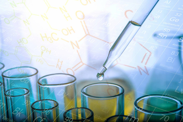 Het laten vallen van chemische vloeistof om buis te testen met laboratorium glaswerk achtergrond. Onderzoek- en ontwikkelingsconcept voor wetenschap of chemie.  - Foto, afbeelding