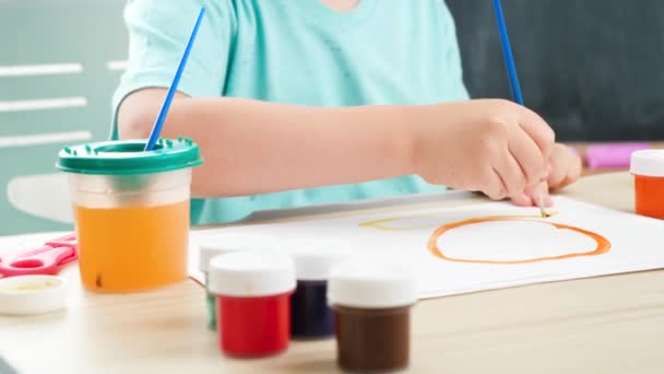 Крупним планом маленький хлопчик малює картину барвистою фарбою за допомогою пензлика. Навчання дітей вдома під час самоізоляції та замикання. Концепція мистецтва та творчості дітей
 - Кадри, відео