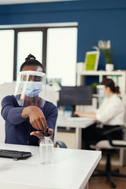Afrikai nő a vállalat irodájában kézi fertőtlenítőt használ - Fotó, kép
