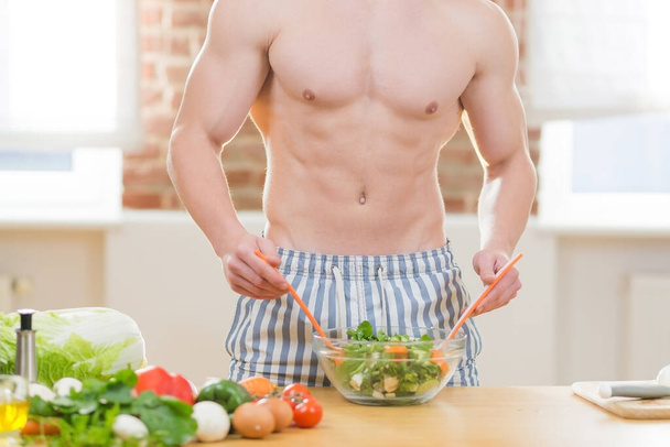Athlete man cooks in the kitchen, uses vegetables and various meats for cooking dinner - Foto, Bild