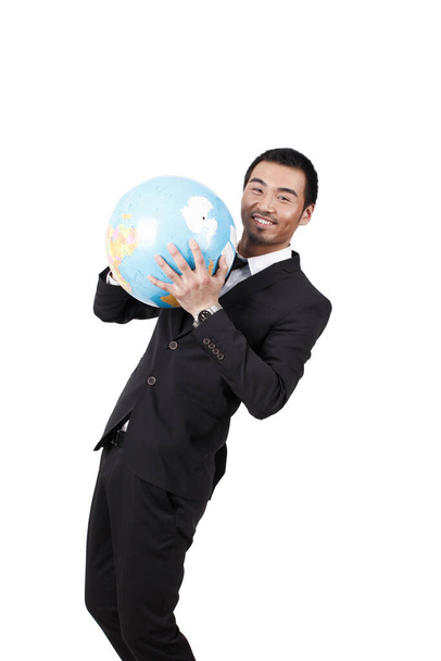 A young business man holding terrestrial globe - Fotó, kép