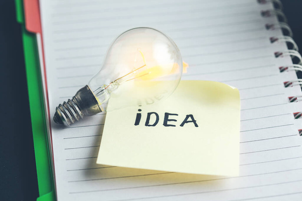 idea text with bulb on notepad - Foto, Imagen