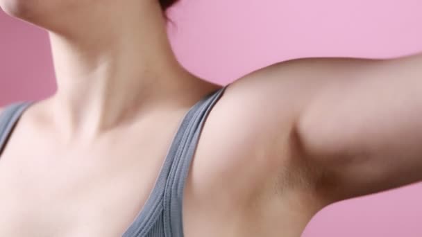 Hygiëne en lichaamsverzorging. Een vrouw brengt een natuurlijk eco deodorant kristal aan op haar oksel. Close-up van de oksel. Roze achtergrond. Bescherming tegen zweten. - Video