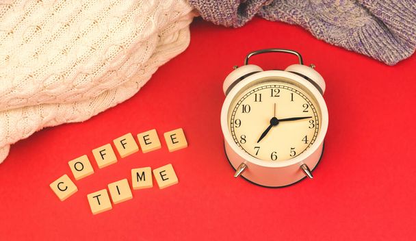 Coffee time morning concept, old vintage alarm clock on red retro background, knitted sweaters photo - Zdjęcie, obraz