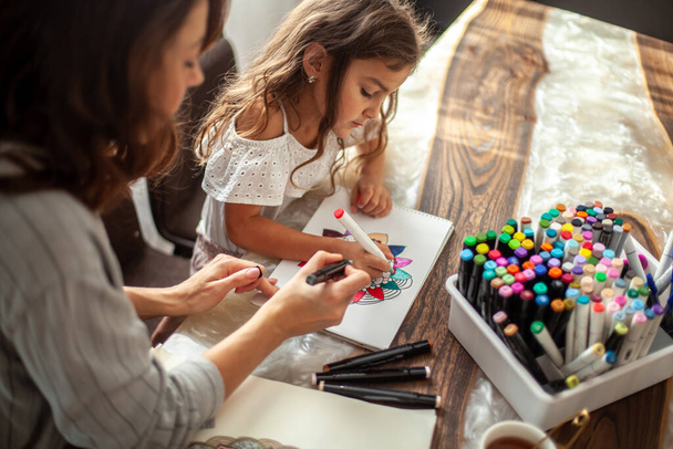 Mom and daughter are doing Zen painting together in their home in the kitchen. Concept for meditation, doodle drawing and hobbies. - Fotoğraf, Görsel