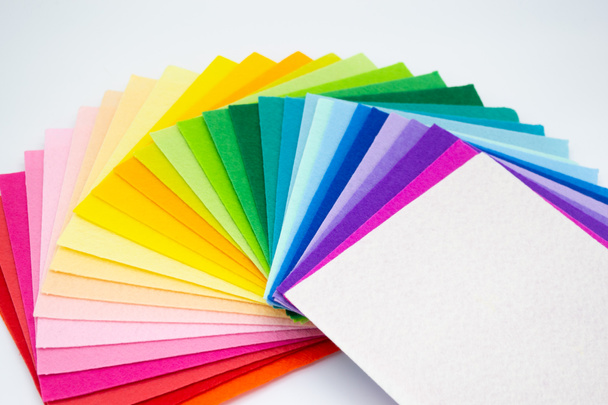 De vierkante stukken vilt verspreid door een kleurenspectrum op gelijkenis van een regenboog: van tinten rood, roze, geel, groen, blauw en helder wit aan het einde. Kopieerruimte. - Foto, afbeelding