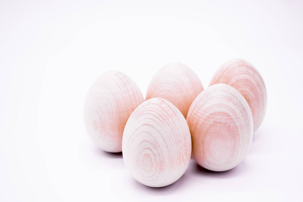 Pięć ręcznie robionych niemalowanych drewnianych jaj na białym tle. - Zdjęcie, obraz