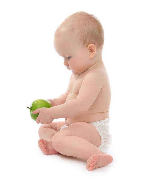 child baby girl toddler sitting eating green apple  - 写真・画像