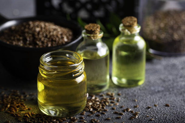 Бутылка льняного масла и льняных семян в миске. - Фото, изображение