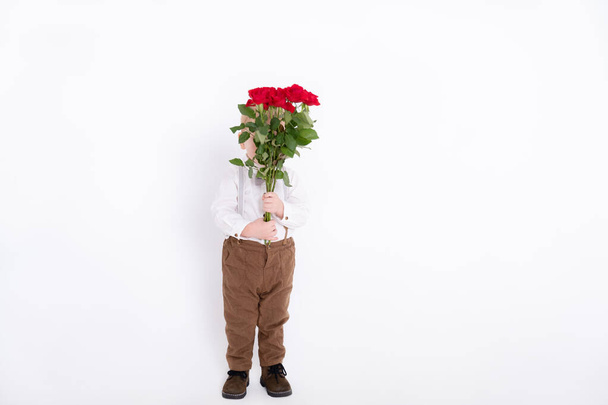 白い背景に赤いバラの花束を持っている赤ん坊の幼児の少年。顔のない - 写真・画像