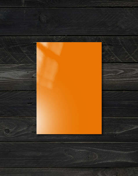 Orange booklet cover isolated on black wood background, mockup template - Fotó, kép