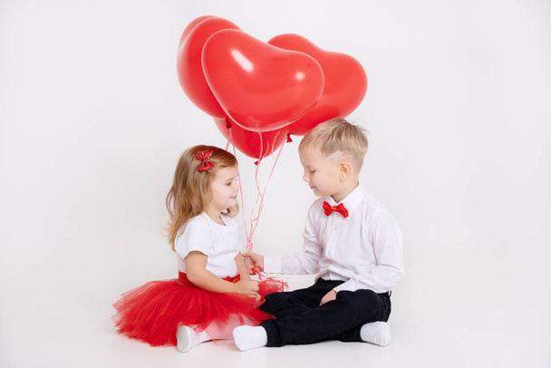 mały chłopiec dając balony serca do dziewczynki maluch na Walentynki na białym tle - Zdjęcie, obraz