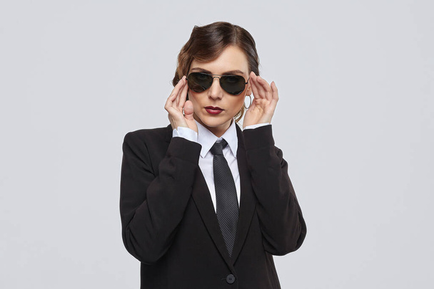 attractive woman with a retro hairstyle poses in a men's suit and sunglasses - Fotó, kép