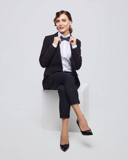 attractive woman with a retro hairstyle poses in a man's suit. photo shoot in the studio on a white background - Photo, Image