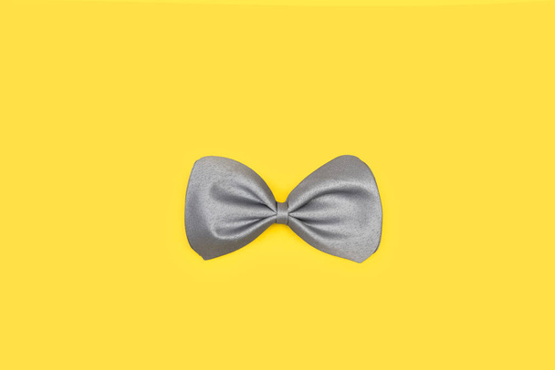 Серый галстук-бабочка на желтом фоне - Фото, изображение