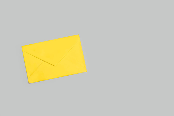 Желтый конверт на сером фоне с копировальным пространством - Фото, изображение