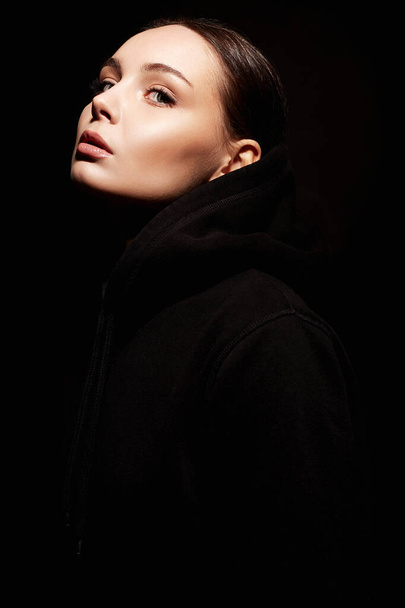 portrait of beautiful young woman in dark. hipster girl in dark weared Hoodie - Foto, imagen