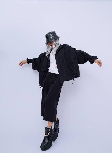 Studio Fashion Portrait Of Girl Ropa de calle en blanco y negro y accesorios elegantes. Sombrero de cubo y botas de plataforma de moda. Concepto minimalista - Foto, Imagen