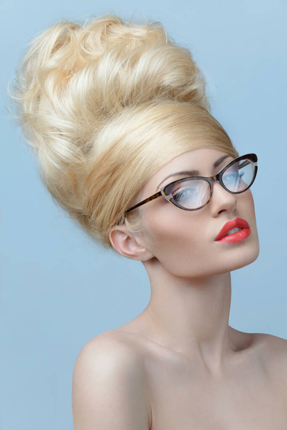 Porträt einer jungen Schönen. Blonde Frau in quadratischer Brille mit nackten Schultern, auf blauem Hintergrund. - Foto, Bild