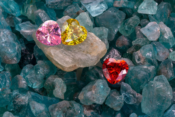 Los diamantes rojos, amarillos y rosados en forma de corazón están en piedras preciosas de color azul cielo crudo. joyas en forma de corazón son regalo encantador para el día de San Valentín - Foto, imagen