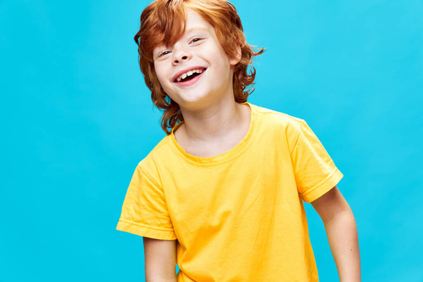 portrait of redhead cheerful boy with open mouth yellow t-shirt cropped view studio - Fotó, kép