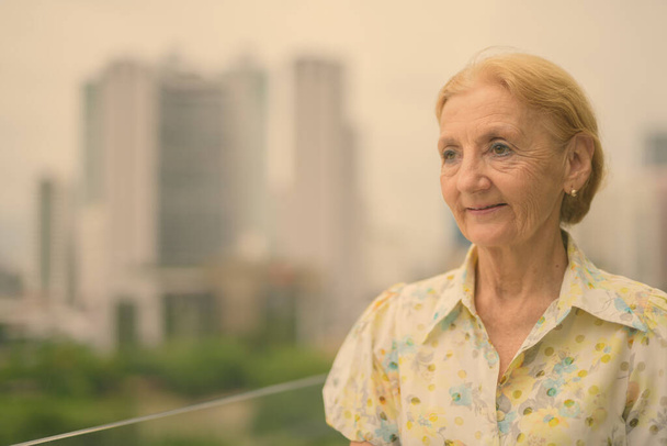 Krásná starší žena s blond vlasy proti pohledu na město - Fotografie, Obrázek