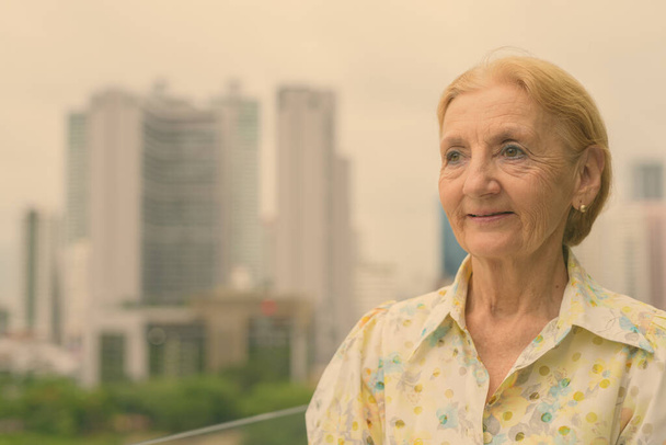 Krásná starší žena s blond vlasy proti pohledu na město - Fotografie, Obrázek