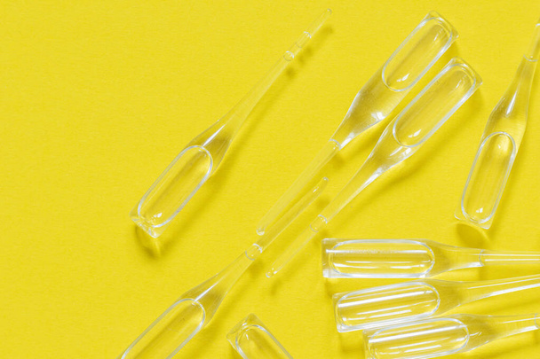 Transparent ampoules, vaccine isolated on yellow background. Top view. Stop coronavirus. Medical and health care concept. - Photo, image