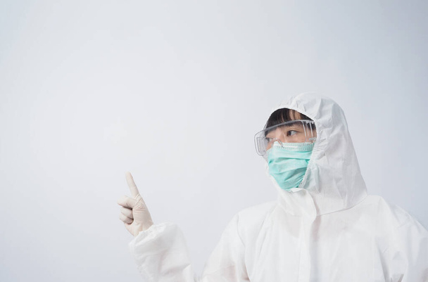 Doctor Gesto. Mujer asiática médico en traje PPE o equipo de protección personal gesto y señalar. guantes de goma médica blanca. gafas de gafas y máscara N95 verde para proteger el coronavirus pandémico. - Foto, imagen