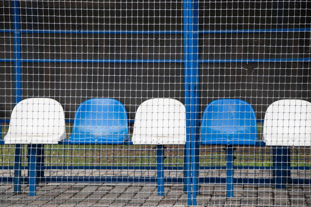 Біло-блакитні стільці для оренди футбольного поля на стадіоні України. - Фото, зображення