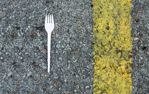 Fourchette en plastique sur asphalte à côté d'une large ligne jaune - Photo, image