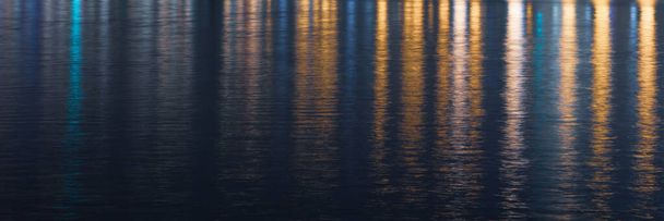 Geceleri renkli ışıklarla yansıtılan su dokusu. Soyut gece arkaplanı, bulanık ışık. Gece görünümü. - Fotoğraf, Görsel