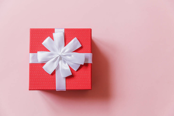 Karácsony újév születésnapja Valentin-napi ünneplés jelen romantikus koncepció. Egyszerűen minimális design piros ajándék doboz elszigetelt pasztell rózsaszín színes háttér. Lapos feküdt felső nézet másolási hely - Fotó, kép