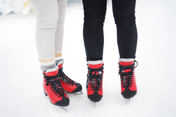 Крупный план девушек, стоящих в красных коньках на ледовой арене. Зимние мероприятия. Зимние развлечения - Фото, изображение