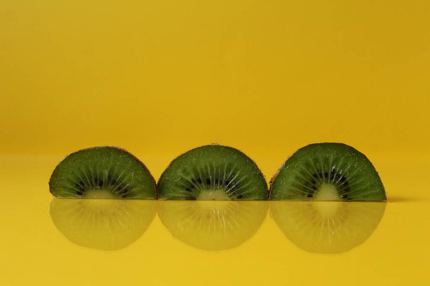 pieces of kiwi halves with a trend of Illuminating yellow color with a place to insert a copyspace. - Foto, Imagem