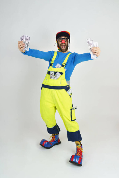 Humor and fun concept. Clown in a bright suit holds money in his hands - Fotografie, Obrázek