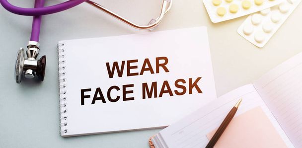 Wear face mask written in white medical notebook - 写真・画像
