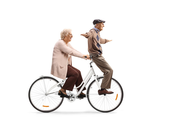 Elderly couple riding on a bicycle isolated on white background - Fotó, kép