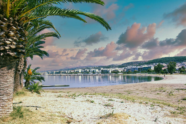 Kréta, Řecko - Širokoúhlý pohled na jezero nebo rybník proti městu Agios Nikolaos. Řecké město s jeho odraz na vodě a palmy proti dramatické mraky a hory - Fotografie, Obrázek